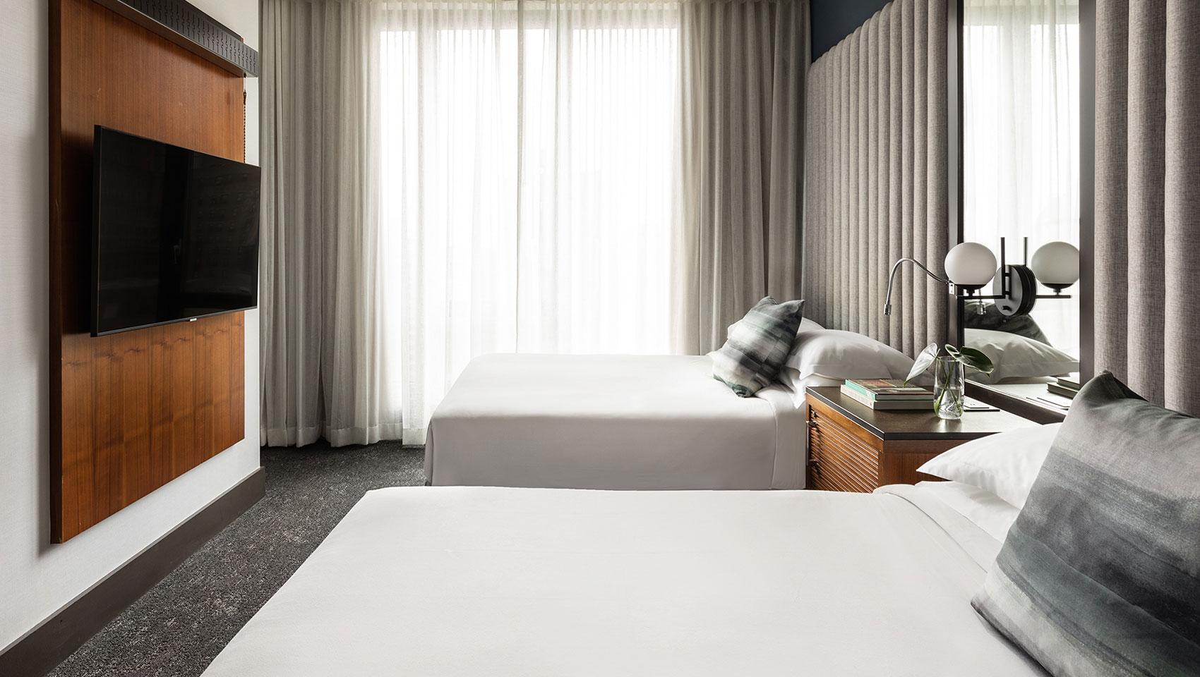 Two side-by-side queen beds with window drapes closed