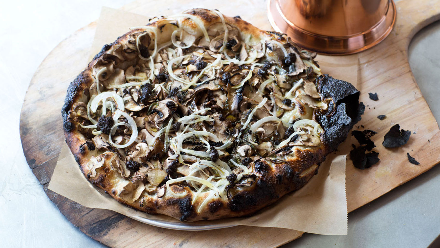 mushroom topped pizza on top of wooden slab