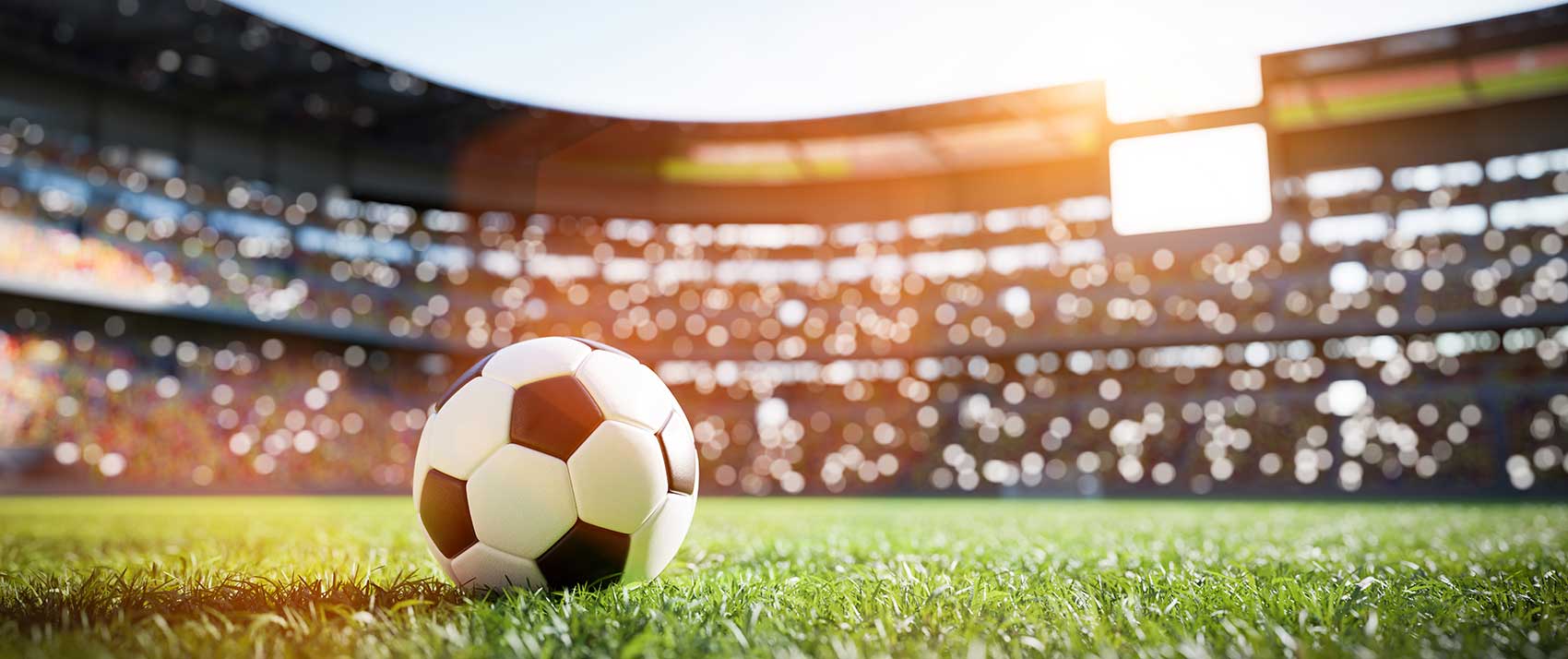 Soccer ball on pitch with stadium in background